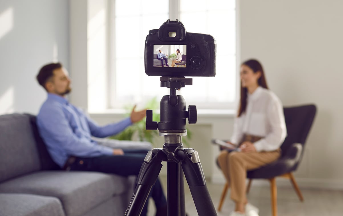 Close up photo of professional camera recording live podcast video interview of two bloggers.